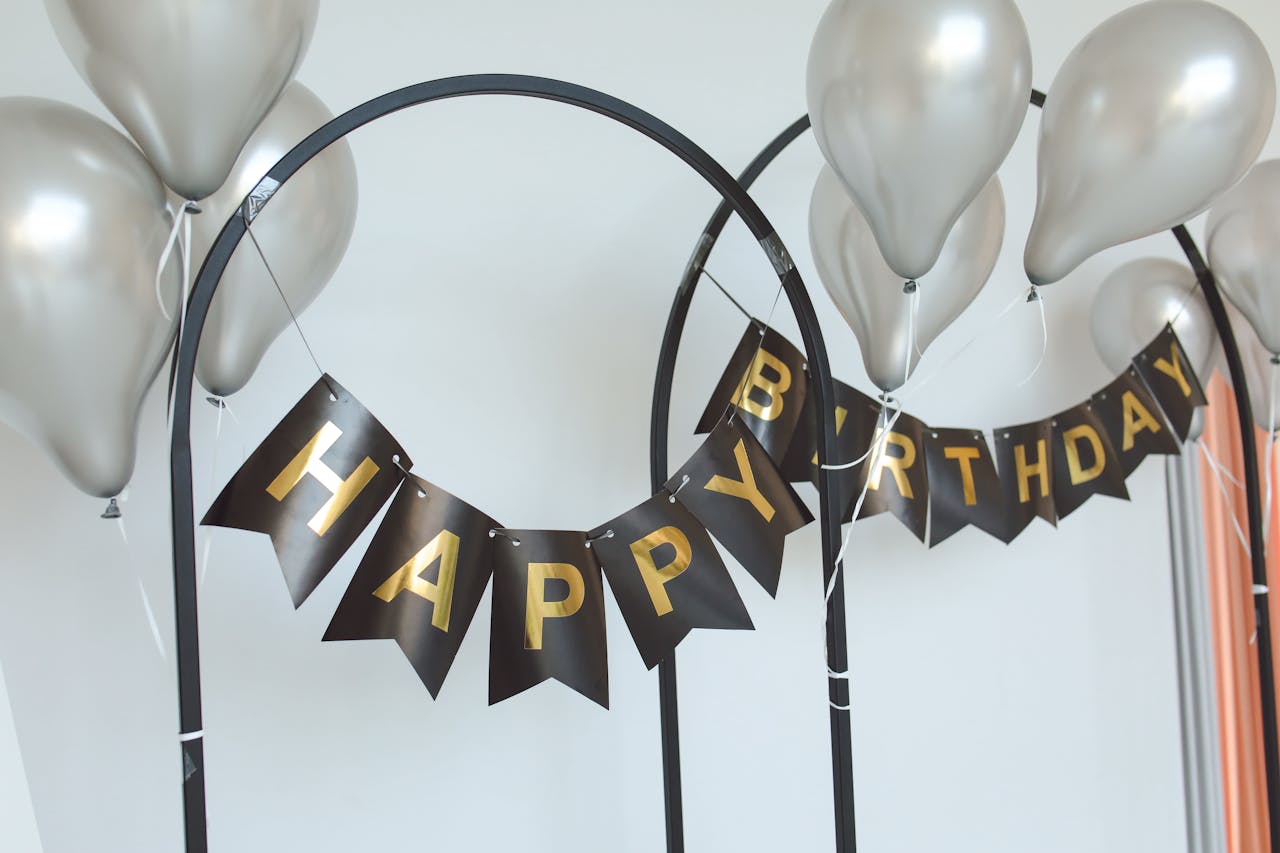 Elegant birthday setup with metallic balloons and a stylish black and gold banner.